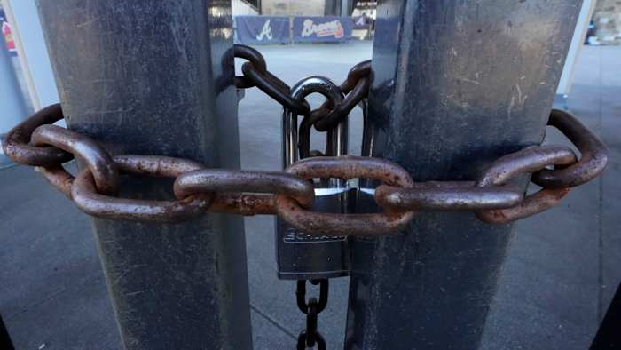 Locked gates are shown at Truist Park, home of the Atlanta Braves baseball team, Wednesday, March 2, 2022, in Atlanta. With owners and players unable to agree on a labor contract to replace the collective bargaining agreement that expired Dec. 1, baseball commissioner Rob Manfred followed through with his threat on Tuesday and canceled the first two series for each of the 30 major league teams. (AP Photo/John Bazemore)